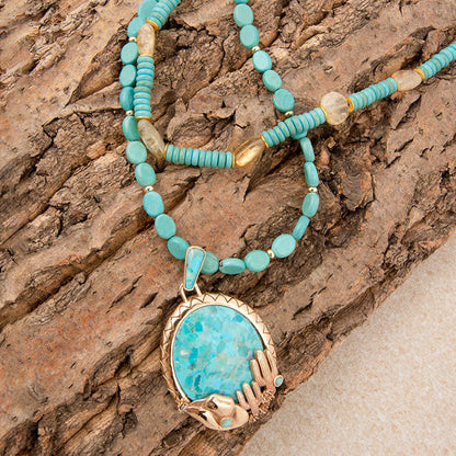 Turquoise beaded necklace with a large turquoise stone pendant on a wooden surface
