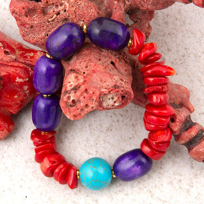 Beaded bracelet with purple, red, and turquoise beads on a coral and sand background
