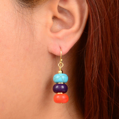 Close-up of an ear wearing a colorful beaded earring with a plain background