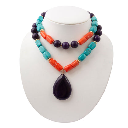 Colorful beaded necklace with a large purple pendant on a white stand.