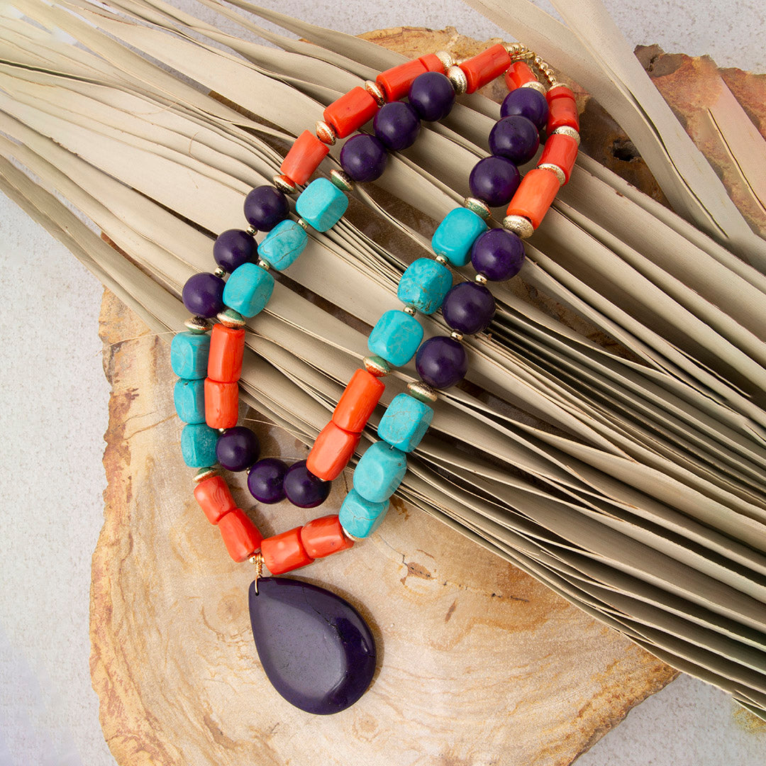 Colorful beaded necklace with a purple pendant on a wooden surface