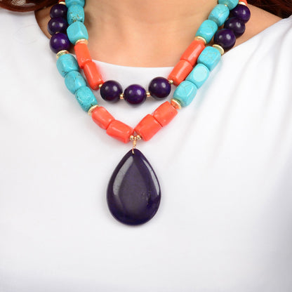 Colorful beaded necklace with a large purple teardrop pendant on a white background