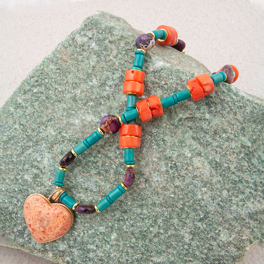 Colorful beaded bracelet with a heart charm on a stone surface
