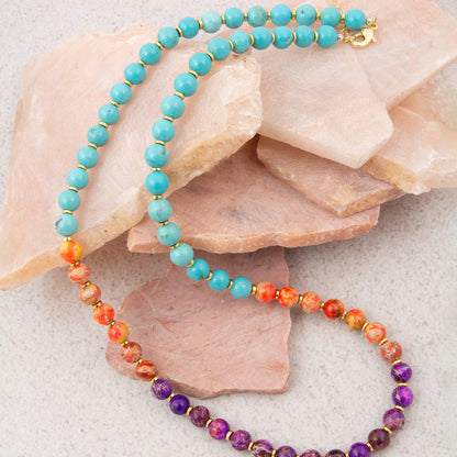 Beaded necklace with turquoise, orange, and purple beads on a stone surface