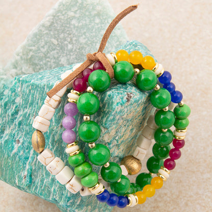 Set of colorful beaded bracelets on a textured stone surface