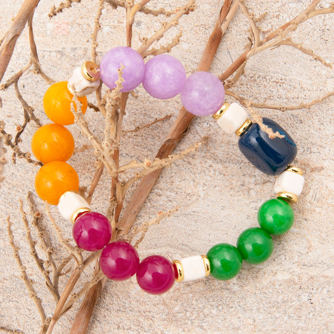 Multicolored beaded bracelet on a sandy background with branches