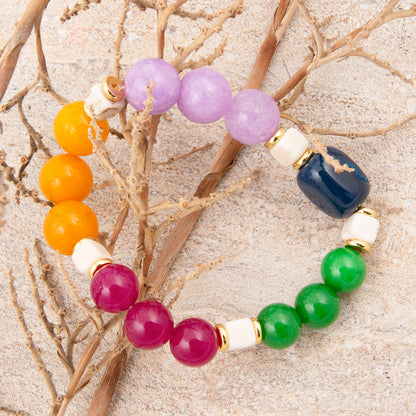 Multicolored beaded bracelet on a sandy background with branches