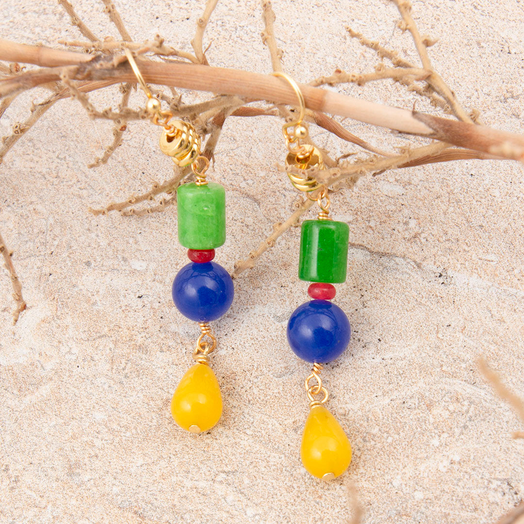 Colorful beaded earrings on a sandy background