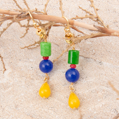 Colorful beaded earrings on a sandy background
