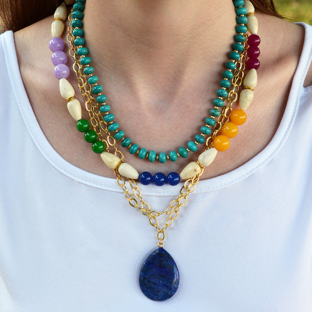 Colorful beaded necklace with a blue pendant on a white background