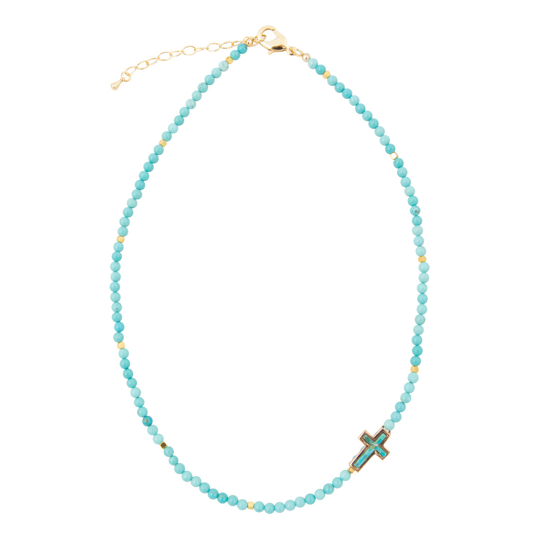 Turquoise beaded necklace with a cross pendant on a white background