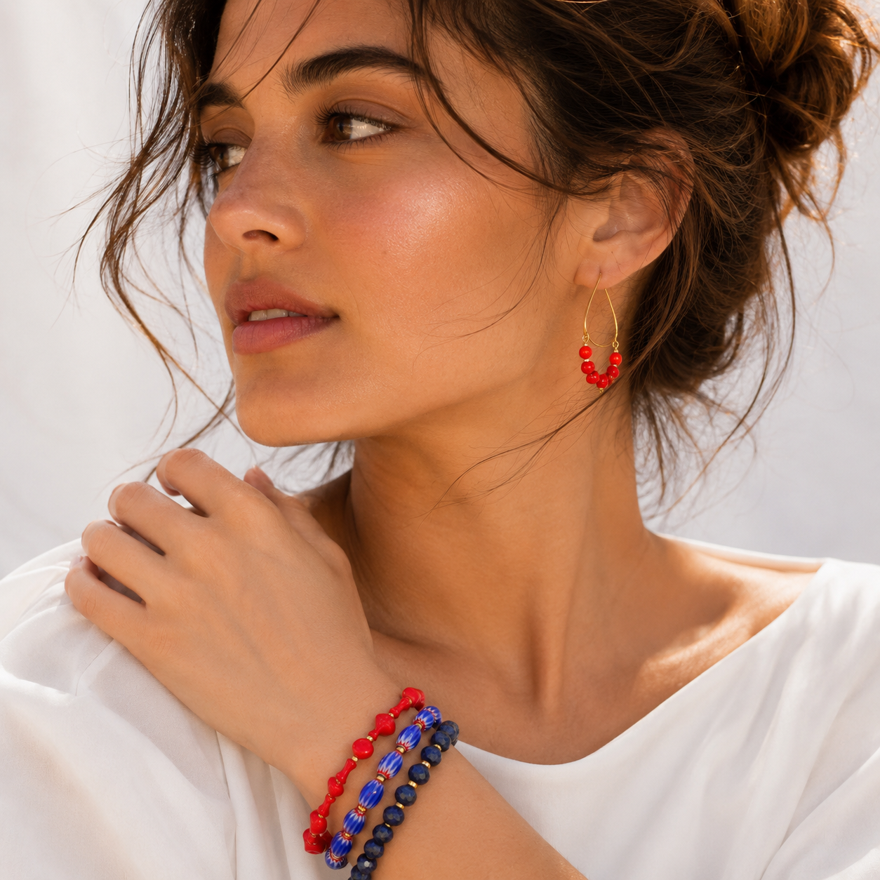 Woman wearing red and blue beaded bracelets on a white background