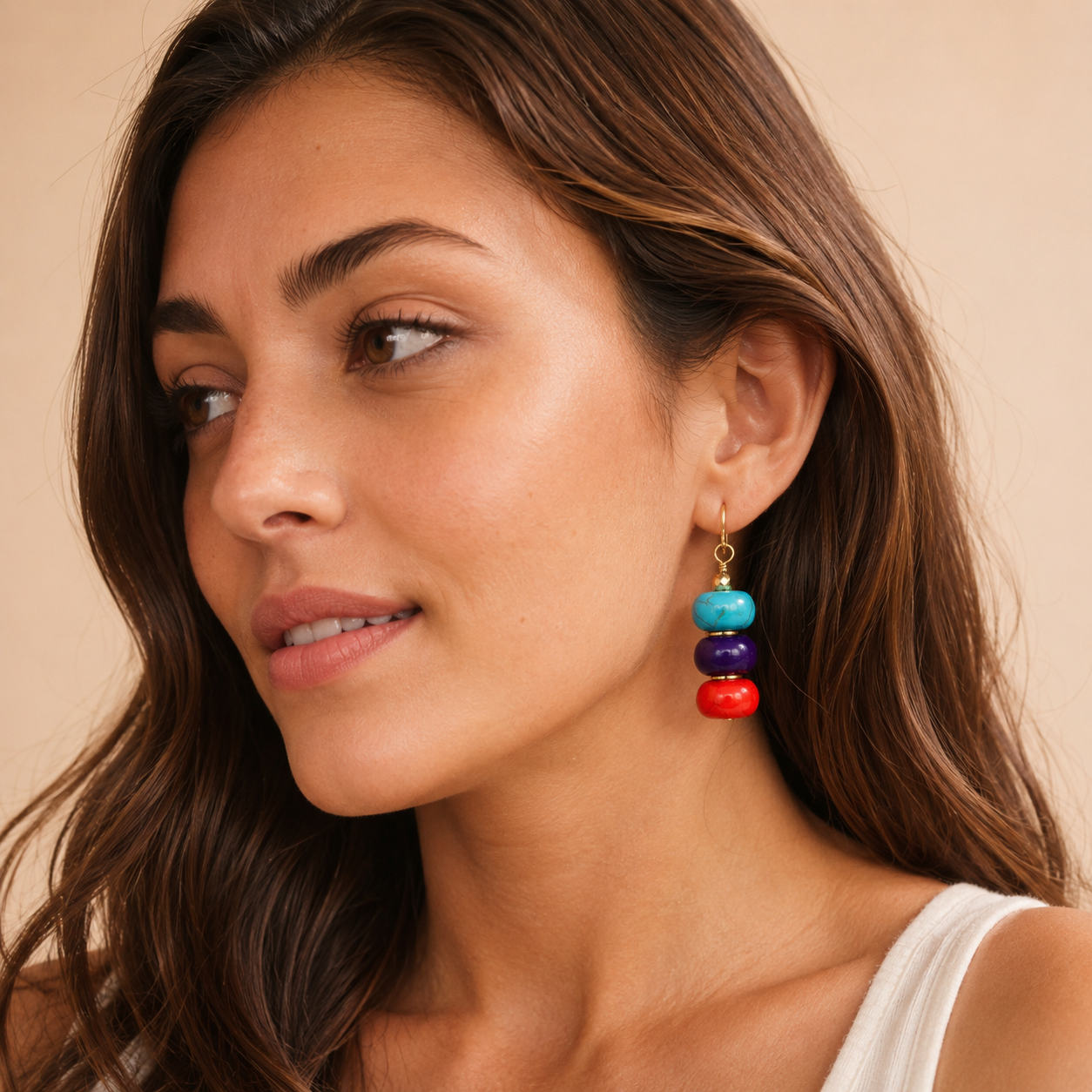 Woman wearing colorful earrings with a neutral background