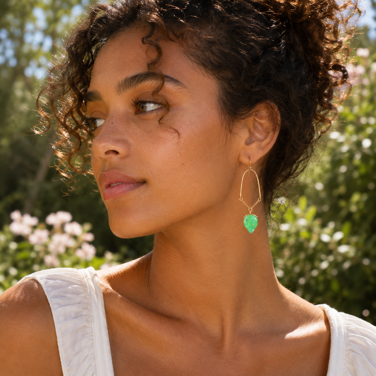 Woman wearing green earrings with a blurred natural background