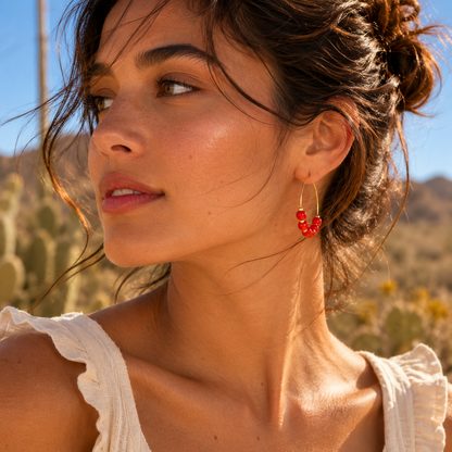 Woman wearing red hoop earrings with a desert landscape in the background