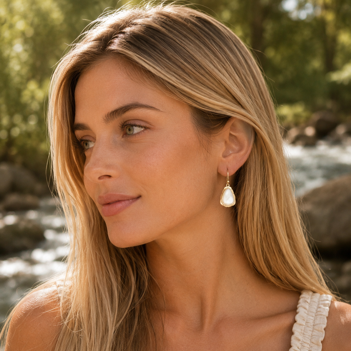 Woman wearing pearl earrings outdoors by a river
