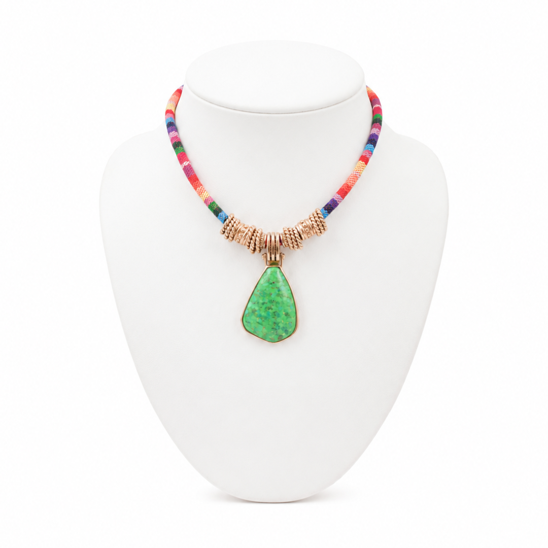 Necklace with a green pendant on a white stand against a white background