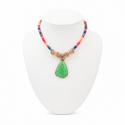 Necklace with a green pendant on a white stand against a white background