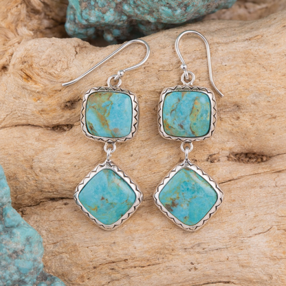 Turquoise earrings with silver settings on a wooden surface