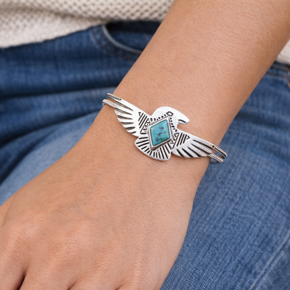 Silver bracelet with turquoise stone on a wrist against a denim background