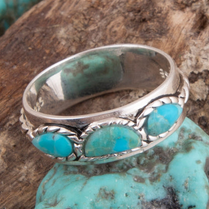 Silver ring with turquoise stones on a wooden surface