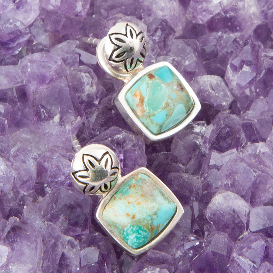 Turquoise and silver earrings on a purple crystal background