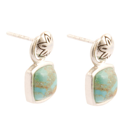 Pair of earrings with turquoise stones and silver accents on a white background