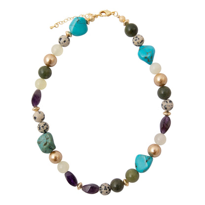 A beaded necklace featuring a mix of polished turquoise, amethyst, olive green, white pearl-like beads, and gold-toned spacers, arranged in a circle on a white background.