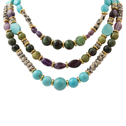 A multi-strand beaded necklace featuring light blue turquoise, olive green, dark green, purple, and gray marbled beads separated by small gold spacer rings, shown on a plain white background.