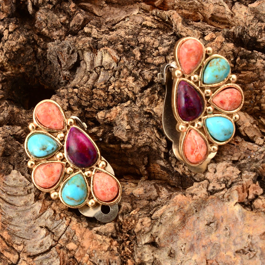 Pair of gold earrings with colorful stones on a wooden surface