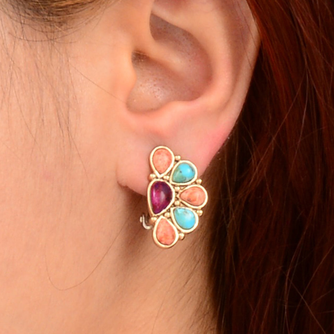 Multicolored gemstone earring worn by a person with red hair.