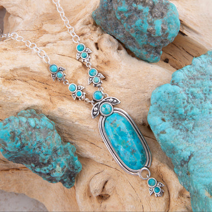 Turquoise necklace with pendant on a wooden surface with turquoise stones