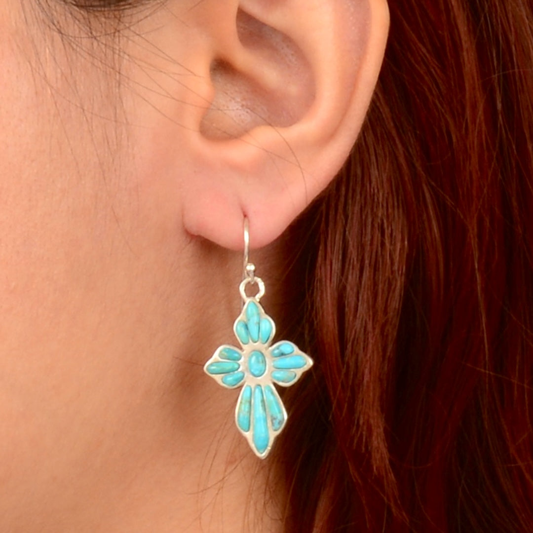 Turquoise flower-shaped earring worn by a person with red hair.