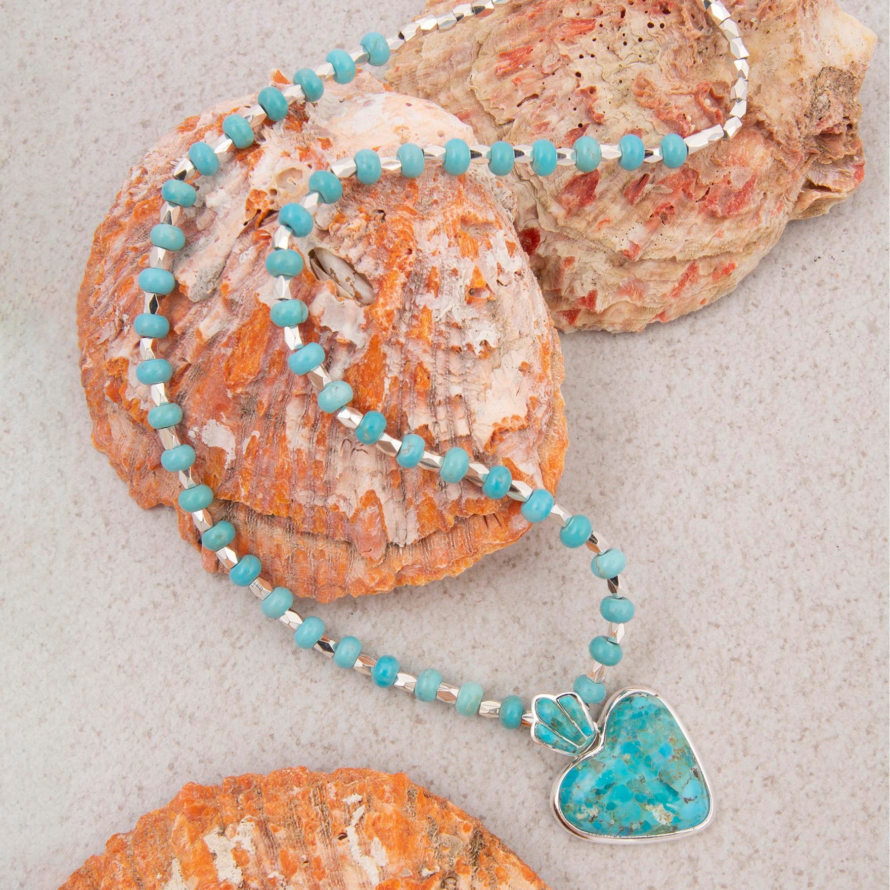 Turquoise beaded necklace with a heart-shaped pendant on seashells.
