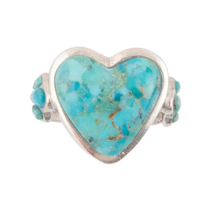A heart-shaped turquoise ring with a silver-toned metal setting and small accent turquoise stones on either side, shown against a plain white background.
