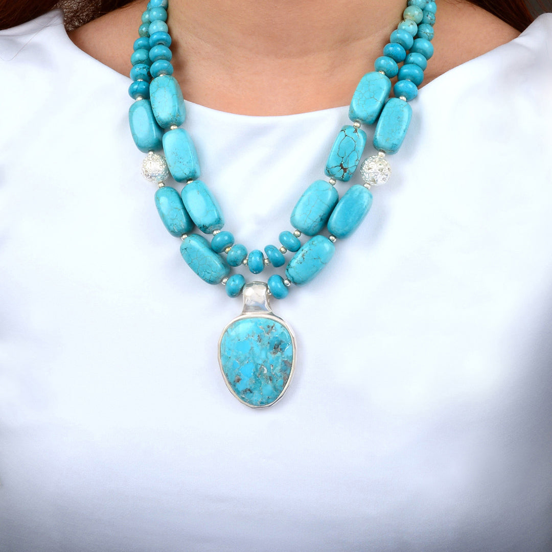 Turquoise beaded necklace with a large pendant on a white background