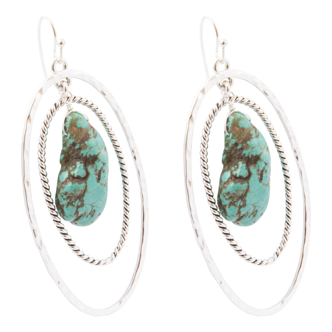 A pair of silver-toned double-ring hoop earrings with a textured, hammered finish and a central turquoise stone featuring brown matrix veining, shown on a plain white background.