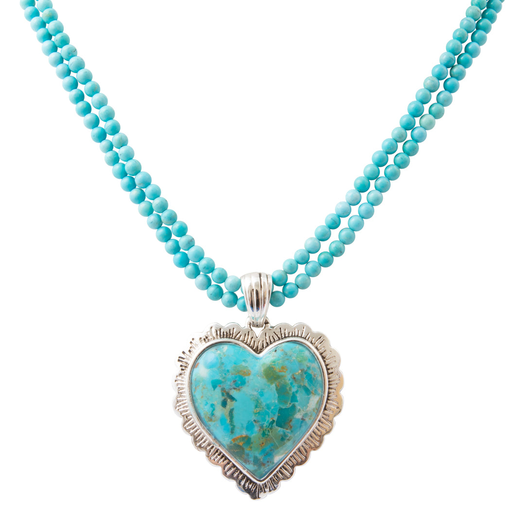 A double-strand turquoise beaded necklace with a heart-shaped turquoise pendant in a textured silver bezel setting, shown against a plain white background.