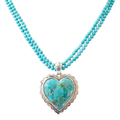 A double-strand turquoise beaded necklace with a heart-shaped turquoise pendant in a textured silver bezel setting, shown against a plain white background.