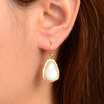 Close-up of a woman wearing a gold earring with a white stone.