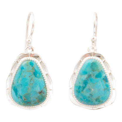 A pair of silver drop earrings featuring teardrop-shaped turquoise stones with natural matrix patterns, set in a scalloped silver bezel with a beaded border.