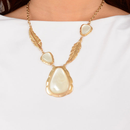 Gold necklace with a large central pearl pendant on a white background