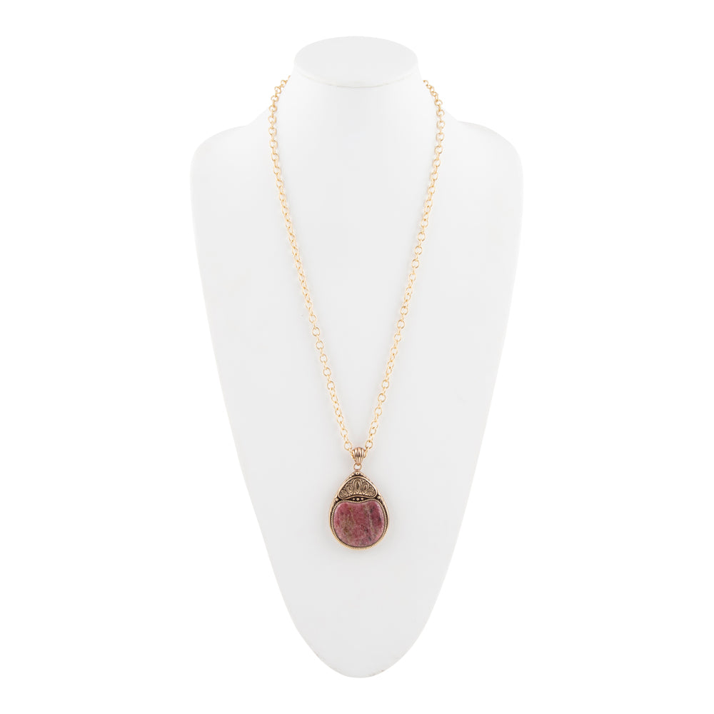 A gold chain necklace with a teardrop-shaped pendant featuring a pinkish-red stone and a textured gold cap, displayed on a white mannequin bust against a white background.