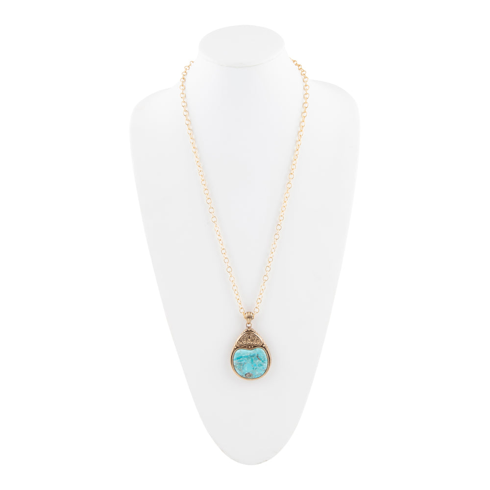 A gold chain necklace with a teardrop-shaped pendant featuring a light blue stone and textured gold settings, displayed on a white neck mannequin.