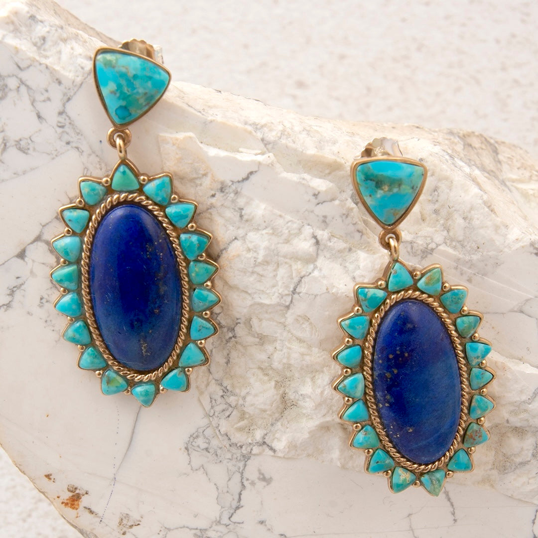 Pair of earrings with blue stones and turquoise accents on a marble surface
