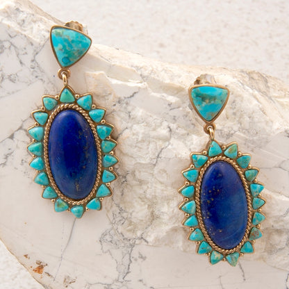 Pair of earrings with blue stones and turquoise accents on a marble surface