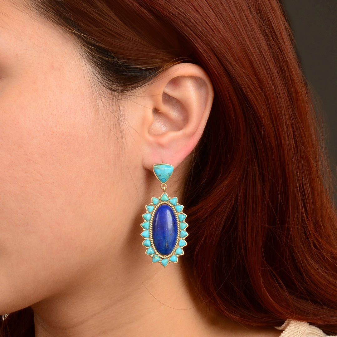 Close-up of a person wearing a blue and turquoise earring with red hair.