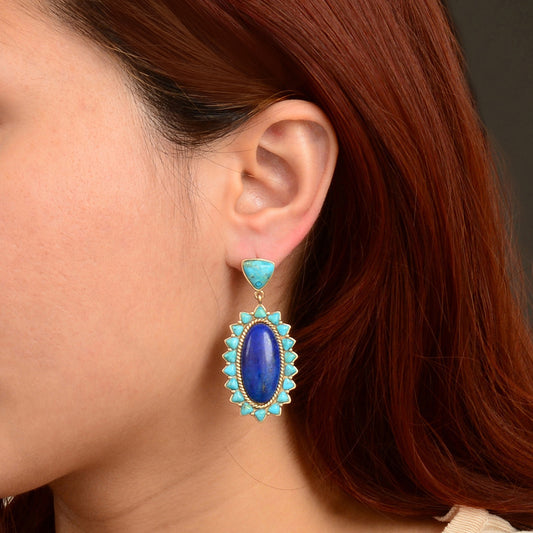 Close-up of a person wearing a blue and turquoise earring with red hair.