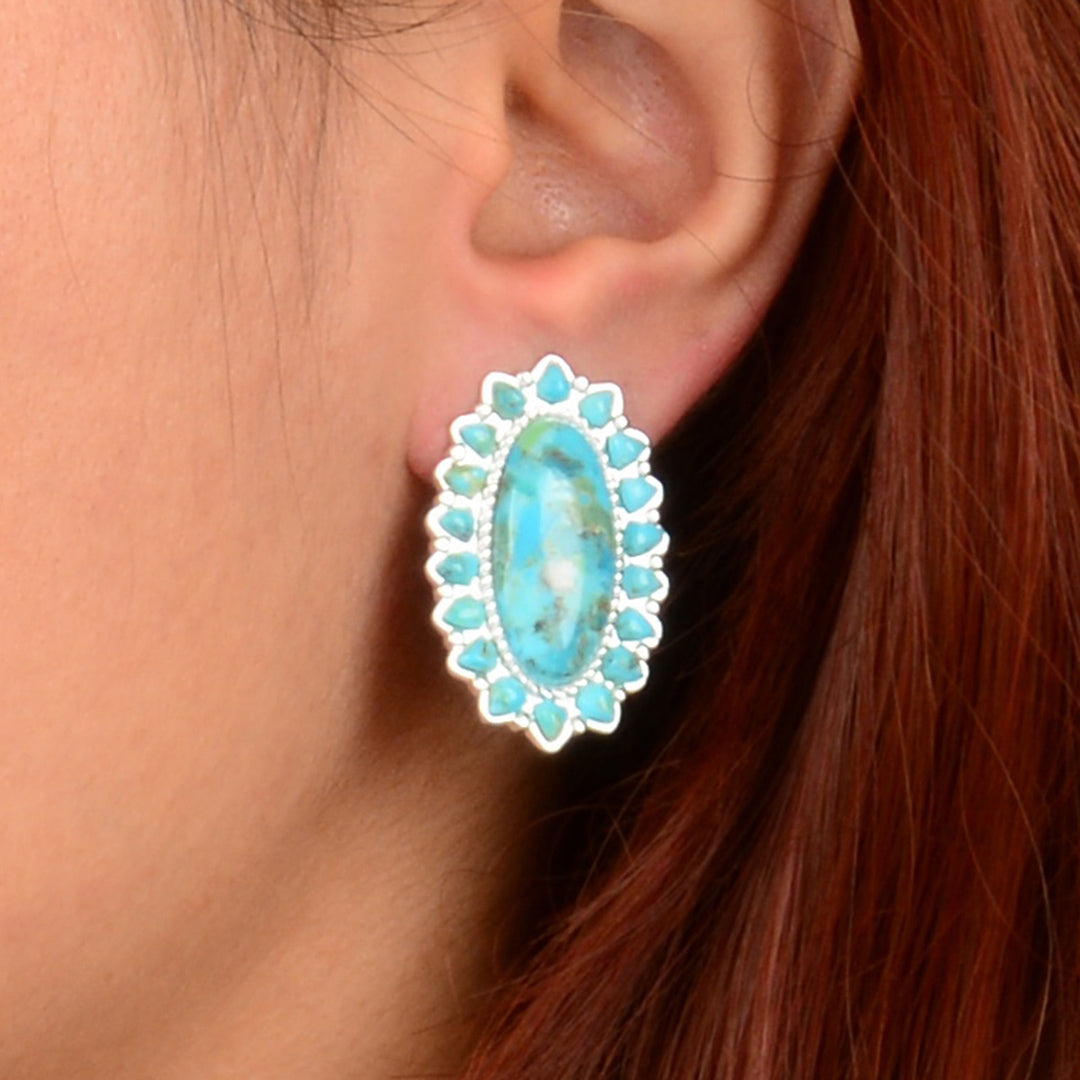 Turquoise earrings worn by a person with red hair