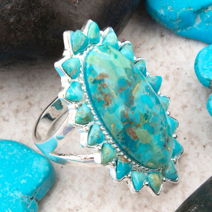 Turquoise stone ring with silver setting on a textured surface with turquoise stones.